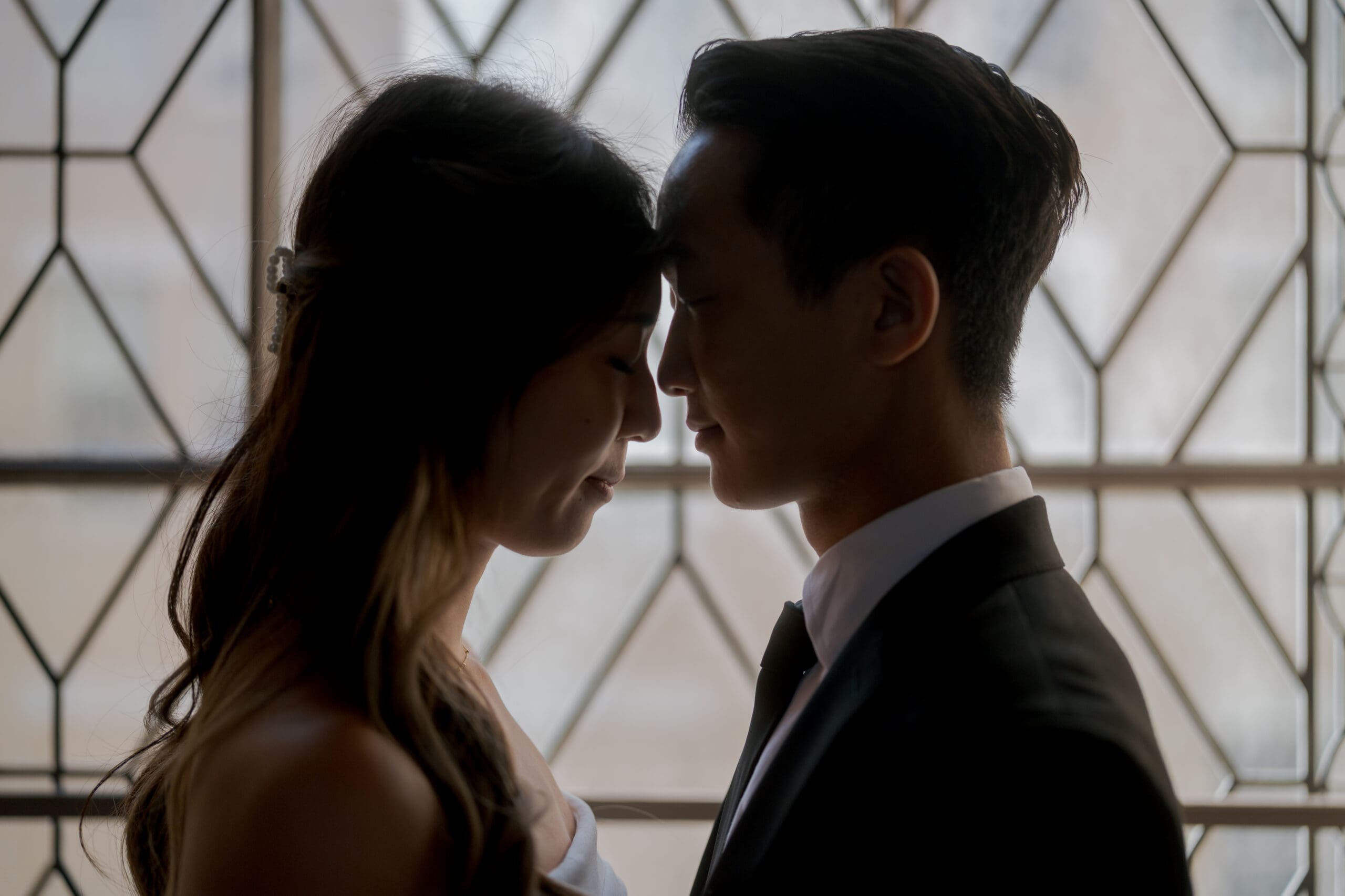 Couple sharing a tender, private moment by the ornate windows on the third floor.