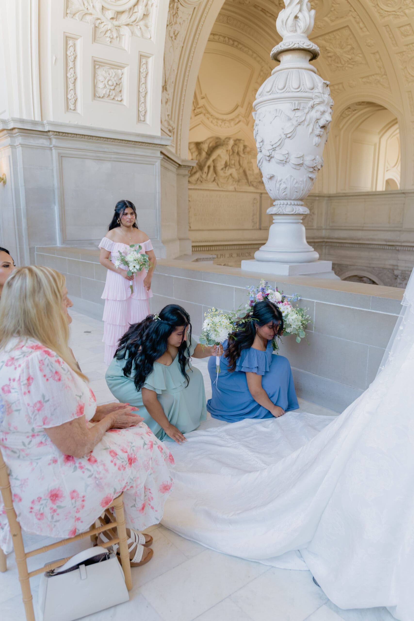 Bridesmaids fix the bride's dress before the wedding ceremony on the 4th floor gallery of San Francisco City Hall