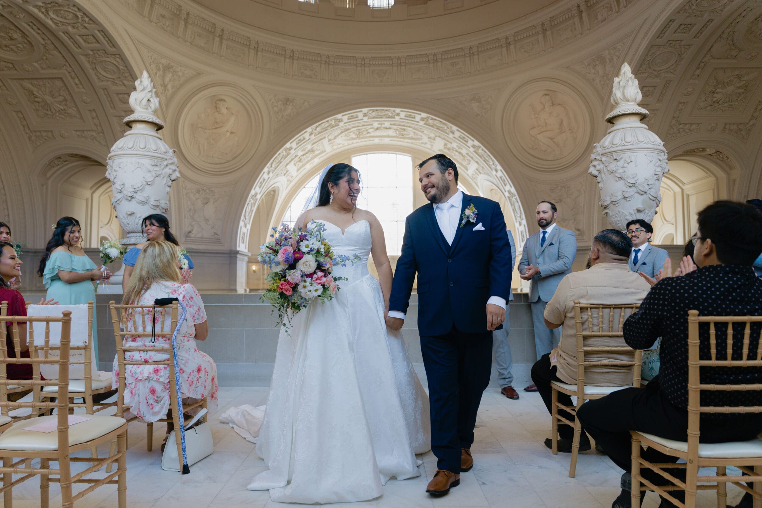 Bride and groom surrounded by loved ones after their wedding ceremony on the 4th floor of SF City Hall