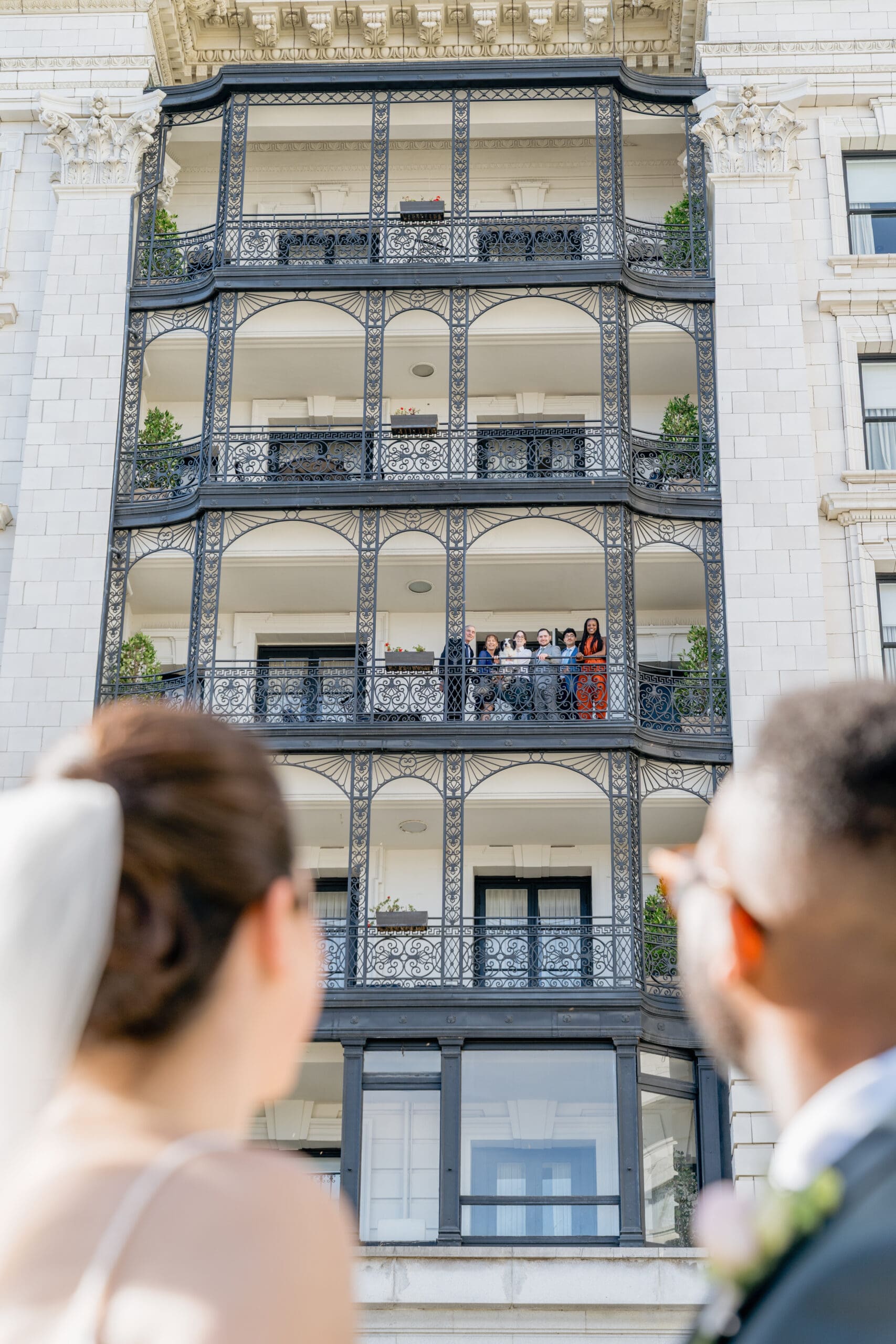 Wedding guests watching the first look from a Fairmont Hotel suite balcony