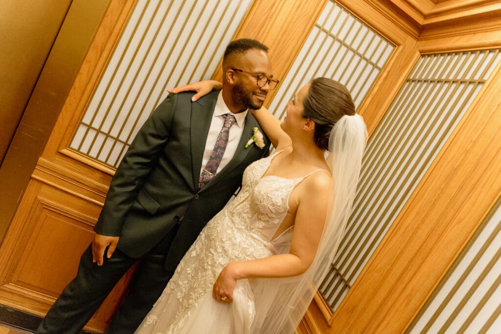 Intimate portrait of a couple inside the vintage wood-paneled elevator at SF City Hall.