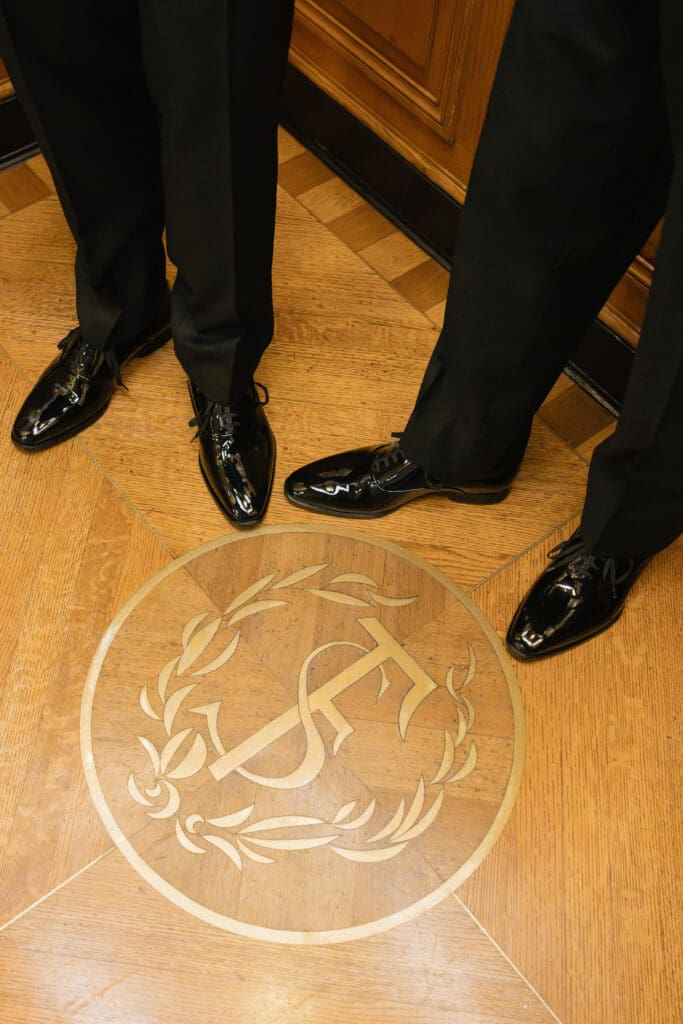 Close-up of a couple’s shoes on the decorative brass floor emblem of the City Hall elevators.