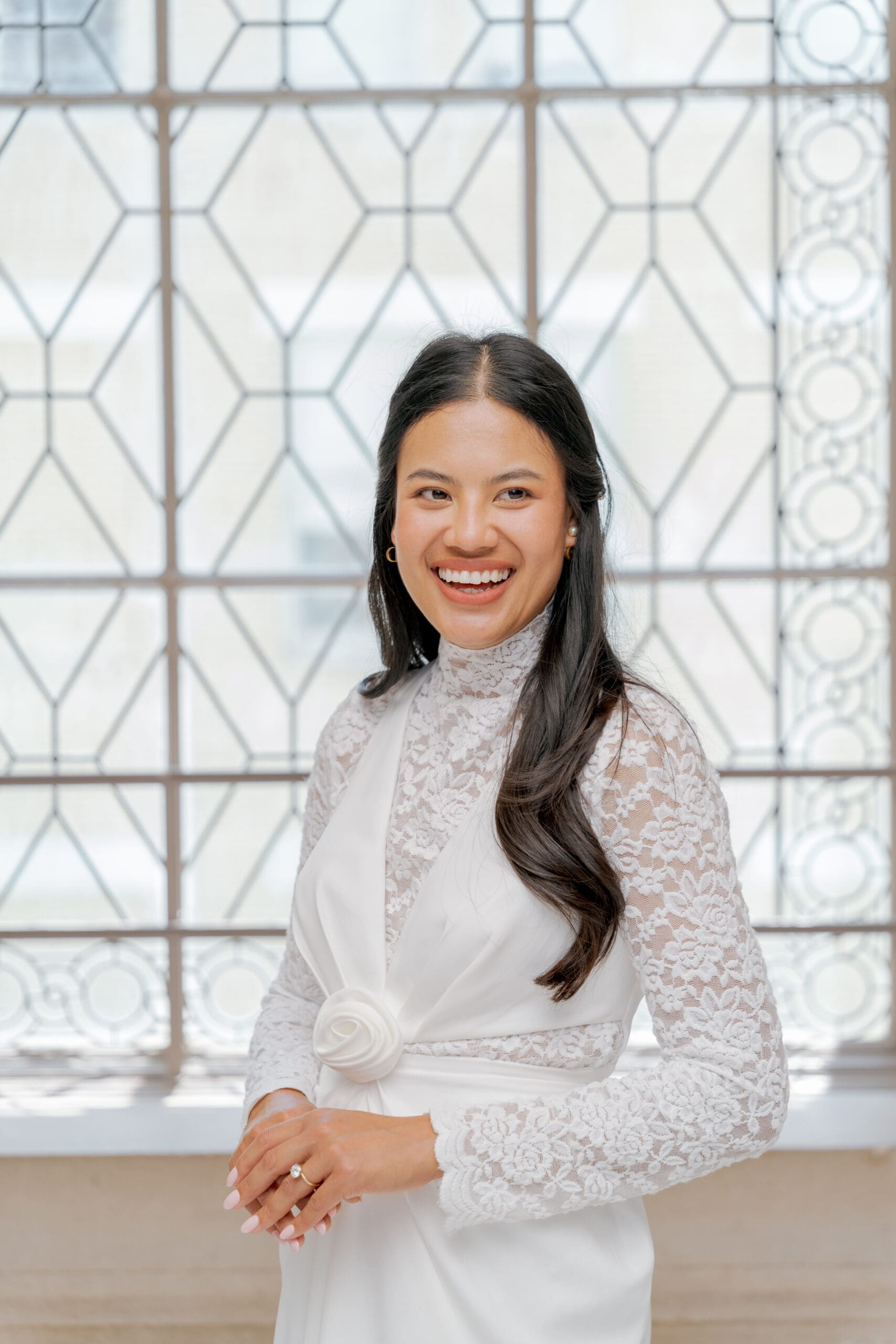 Close-up of a bride's lace wedding dress texture against the iconic windows of San Francisco City Hall