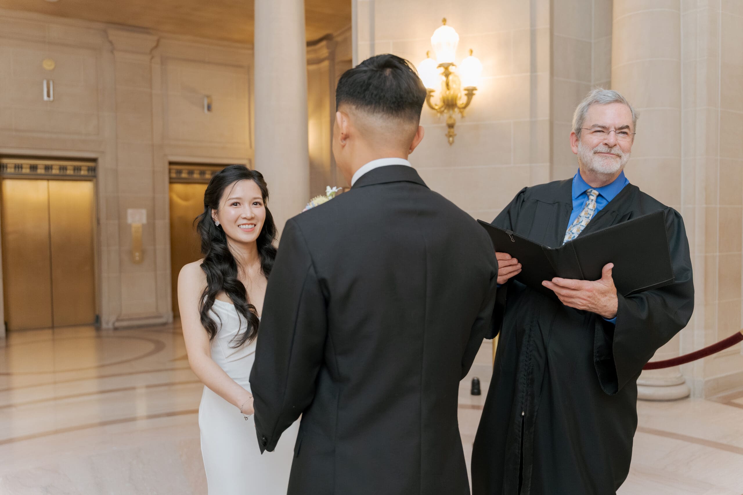 Bride sneaks a smile at the camera just before saying "I Do's" during their SF City Hall Civil Ceremony