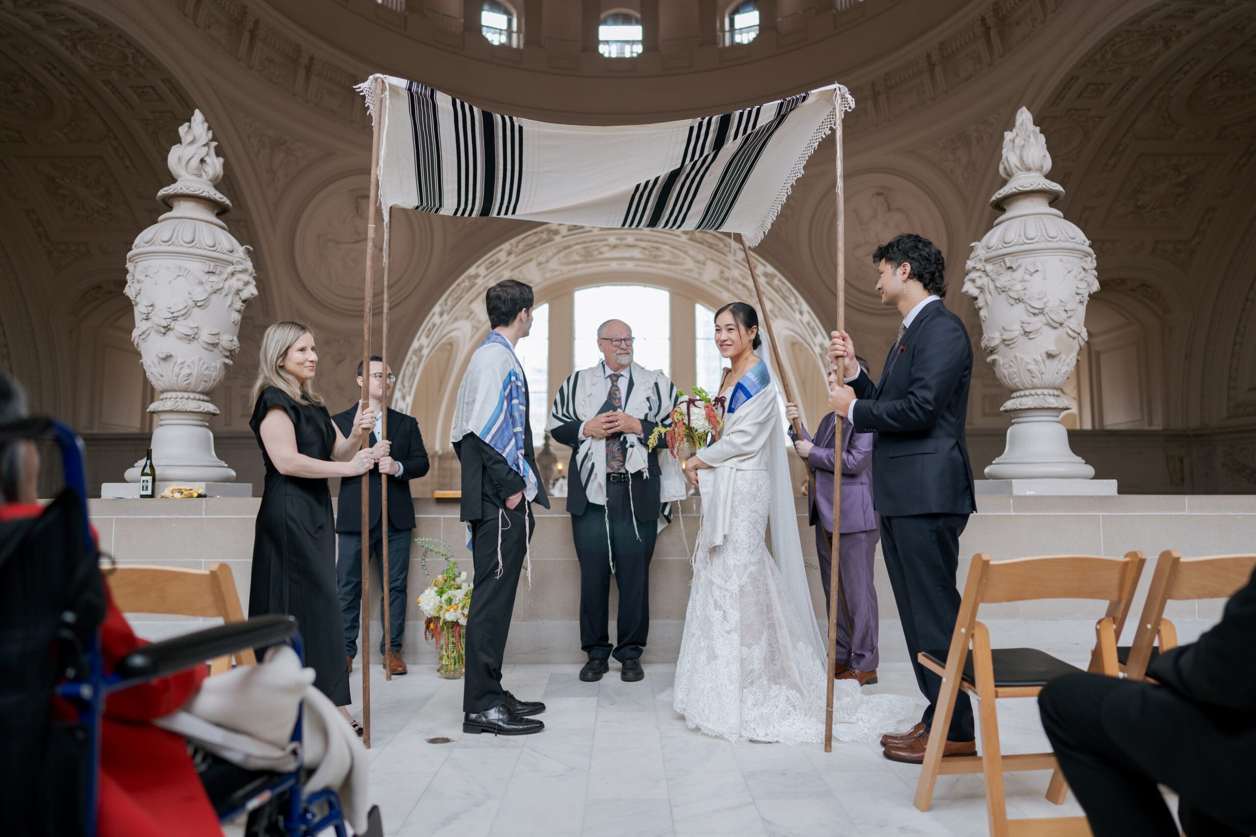 A wedding ceremony at the 4th Floor North Gallery of San Francisco City Hall featuring bright natural light and repetitive stone arches.