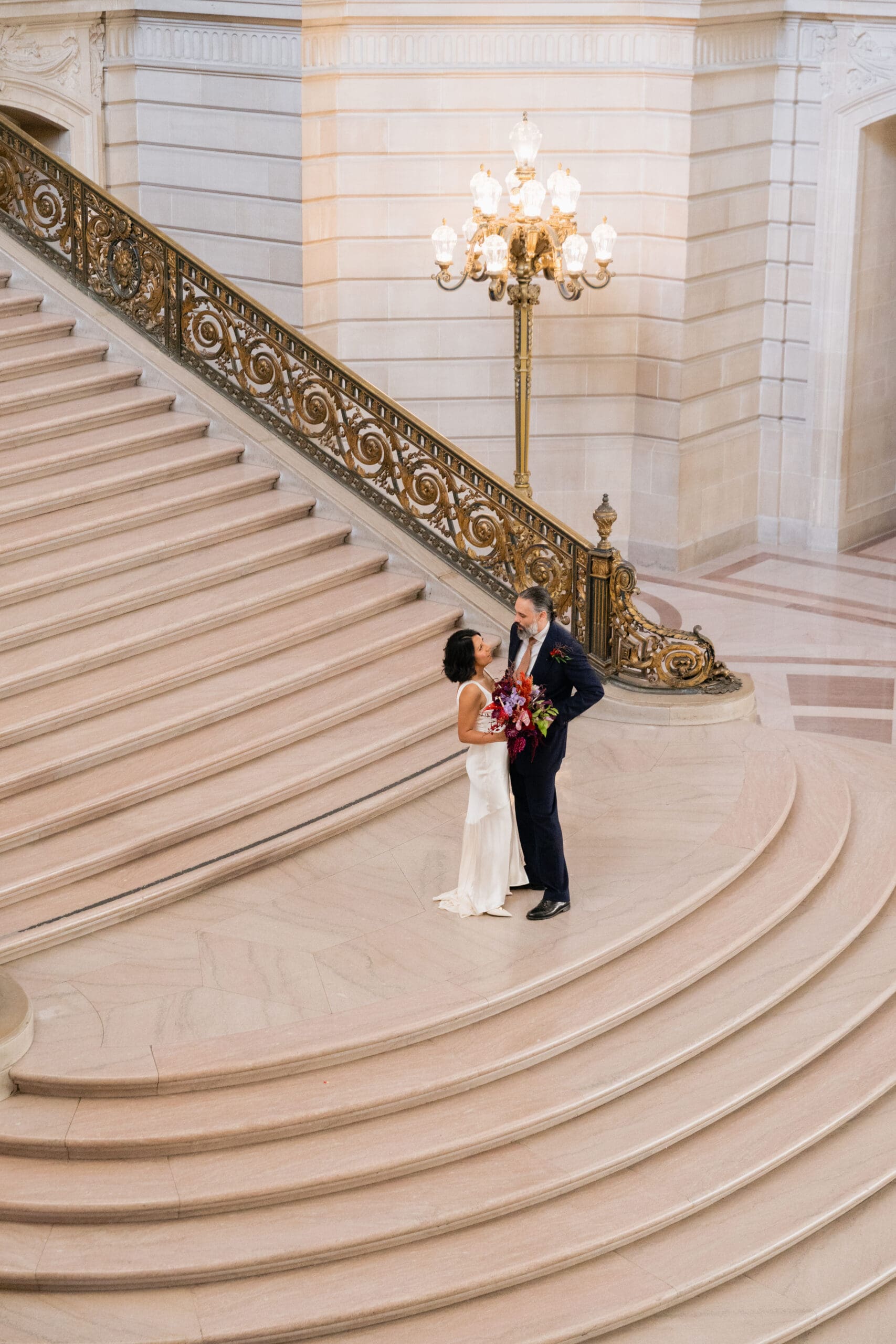 Candid moment of a bride and groom at San Francisco City Hall, grand staircase
