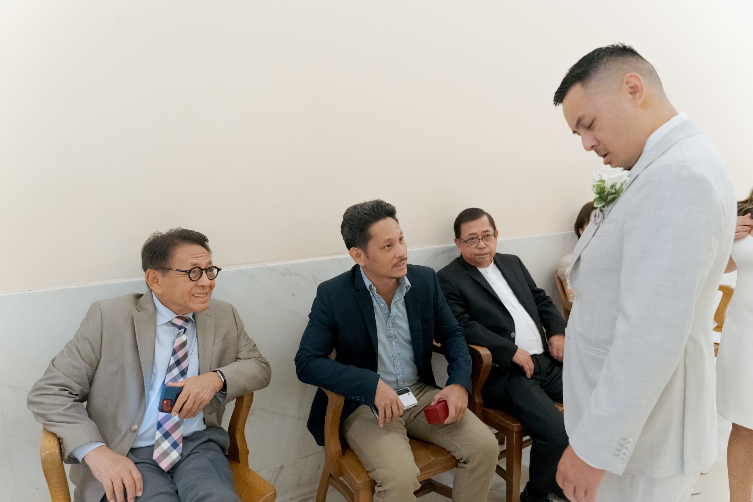 Father and brother of the groom inspecting the groom's boutonniere while waiting for their turn at the County Clerk's office at San Francisco City Hall