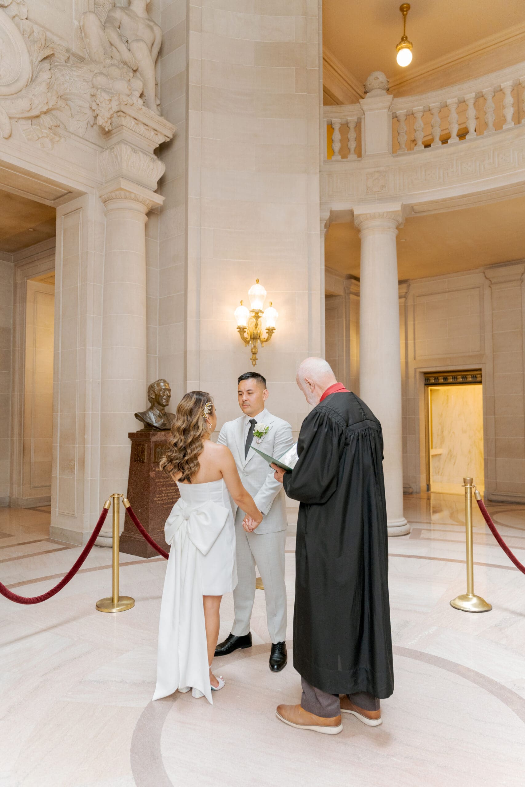 Bride and Groom exchanging vows in the San Francisco City Hall Rotunda during their civil ceremony