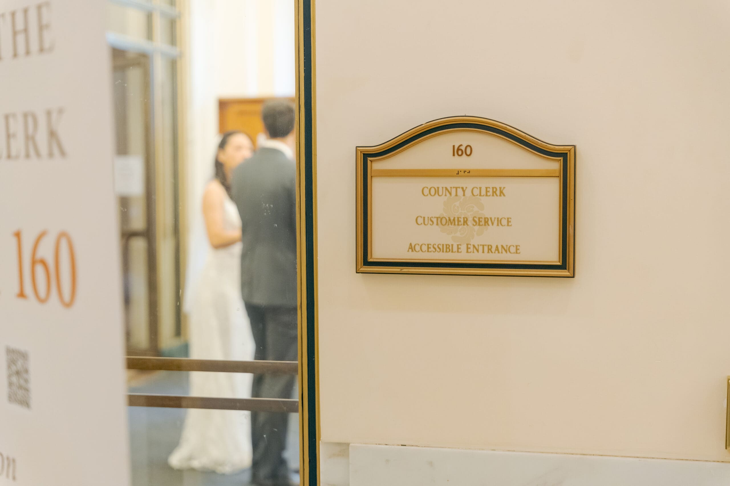 Documentary-style photography of a couple checking in for their marriage appointment at the County Clerk's window.