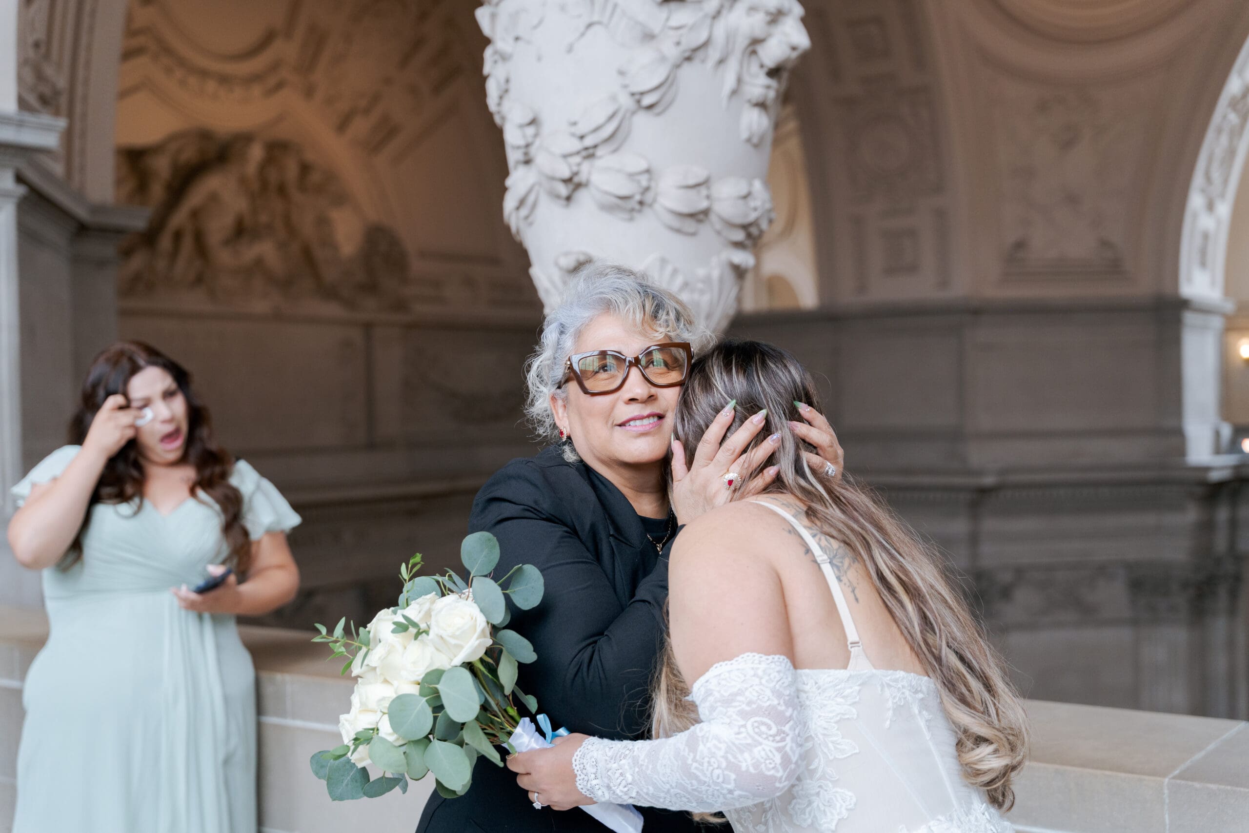 Officiant shares a loving embrace with the bride after a 4th floor private ceremony in SF City Hall