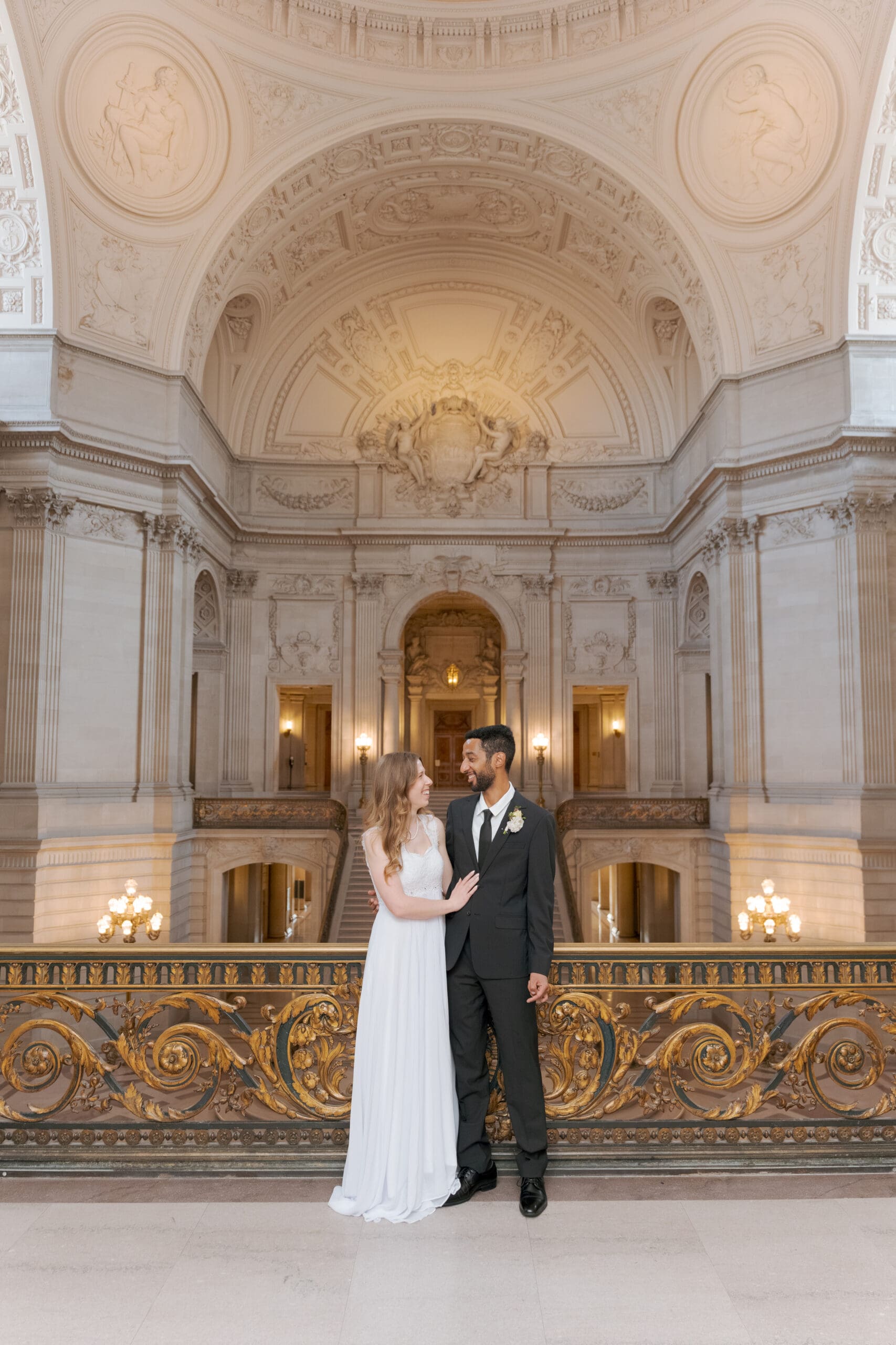 Dramatic wedding portrait on the Mayor's Balcony highlighting the architectural gold leaf detailing and grand staircase view.
