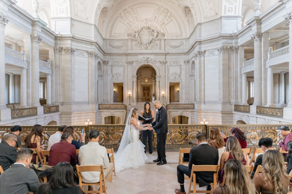 Wedding couple on the Mayor's Balcony with the iconic San Francisco City Hall rotunda and dome in the background.
