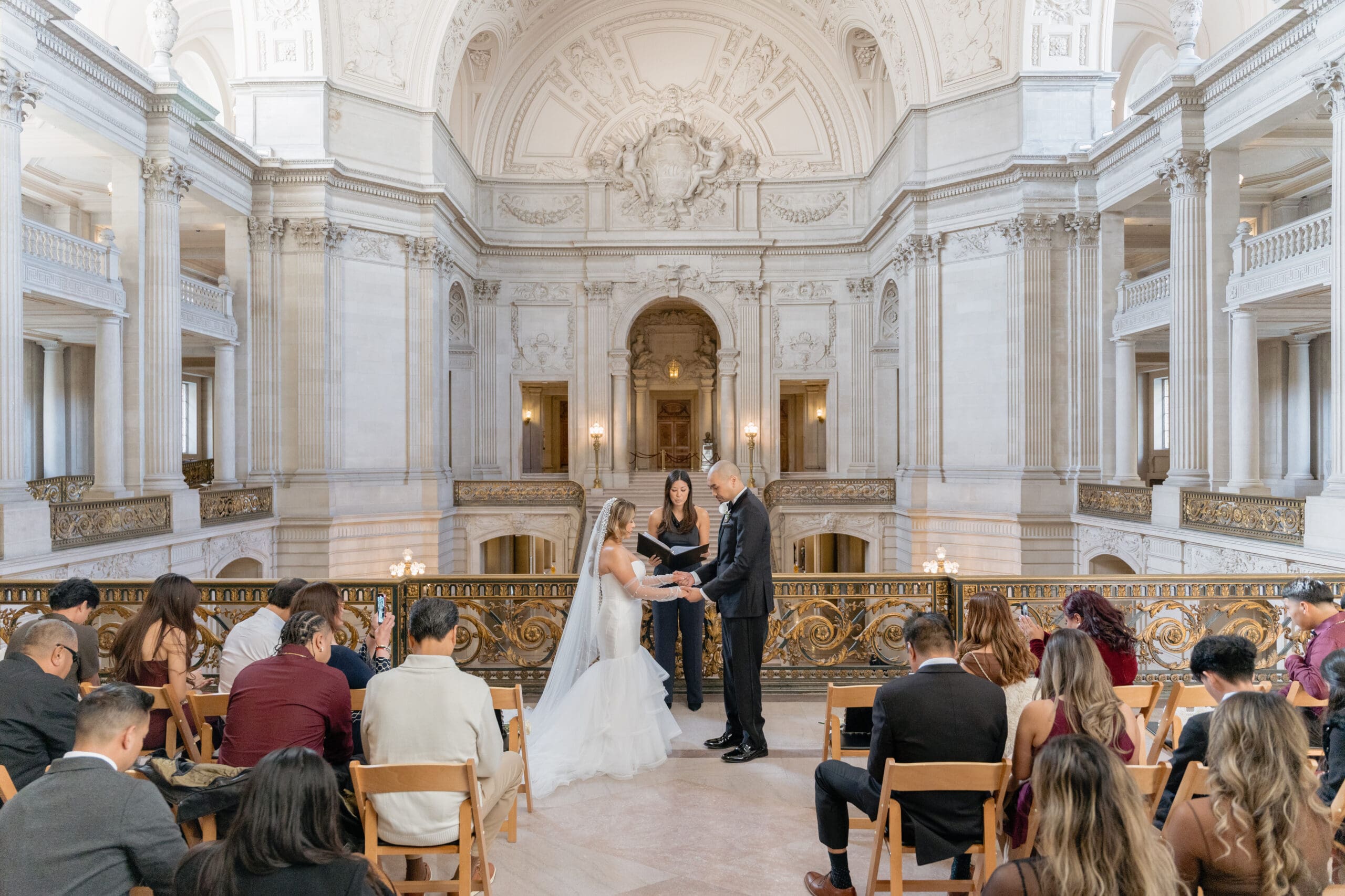 Intimate private wedding ceremony on the Mayor's Balcony of SF City Hall with seated guests and acoustic musician.