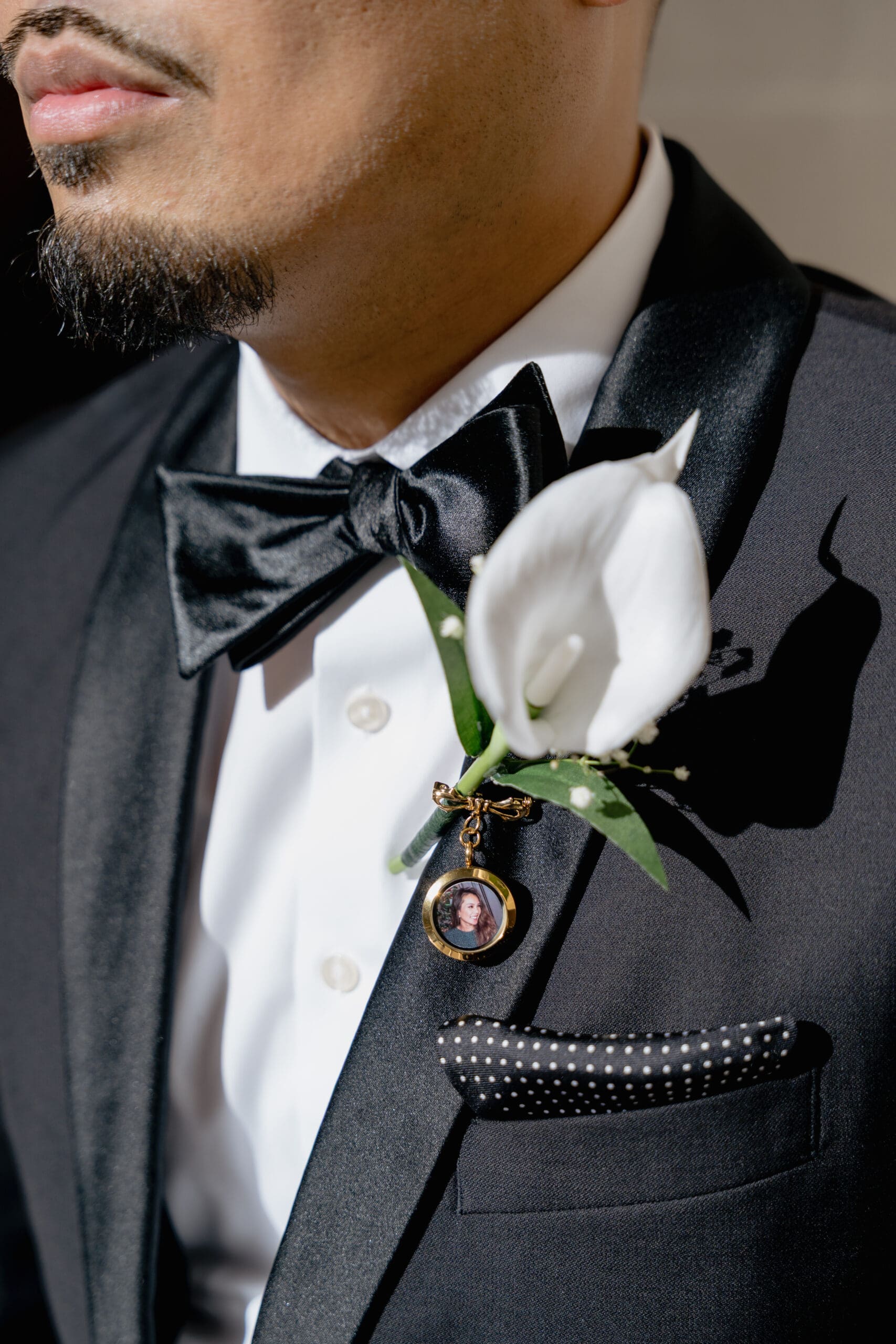 Close-up of a groom's tuxedo details against the historic limestone walls of San Francisco City Hall.