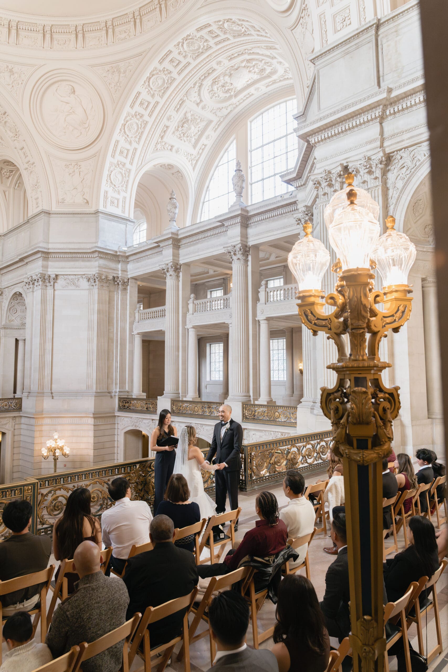 Wide angle view of the Mayor's Balcony at San Francisco City Hall showing the ornate gold railing and rotunda architecture.