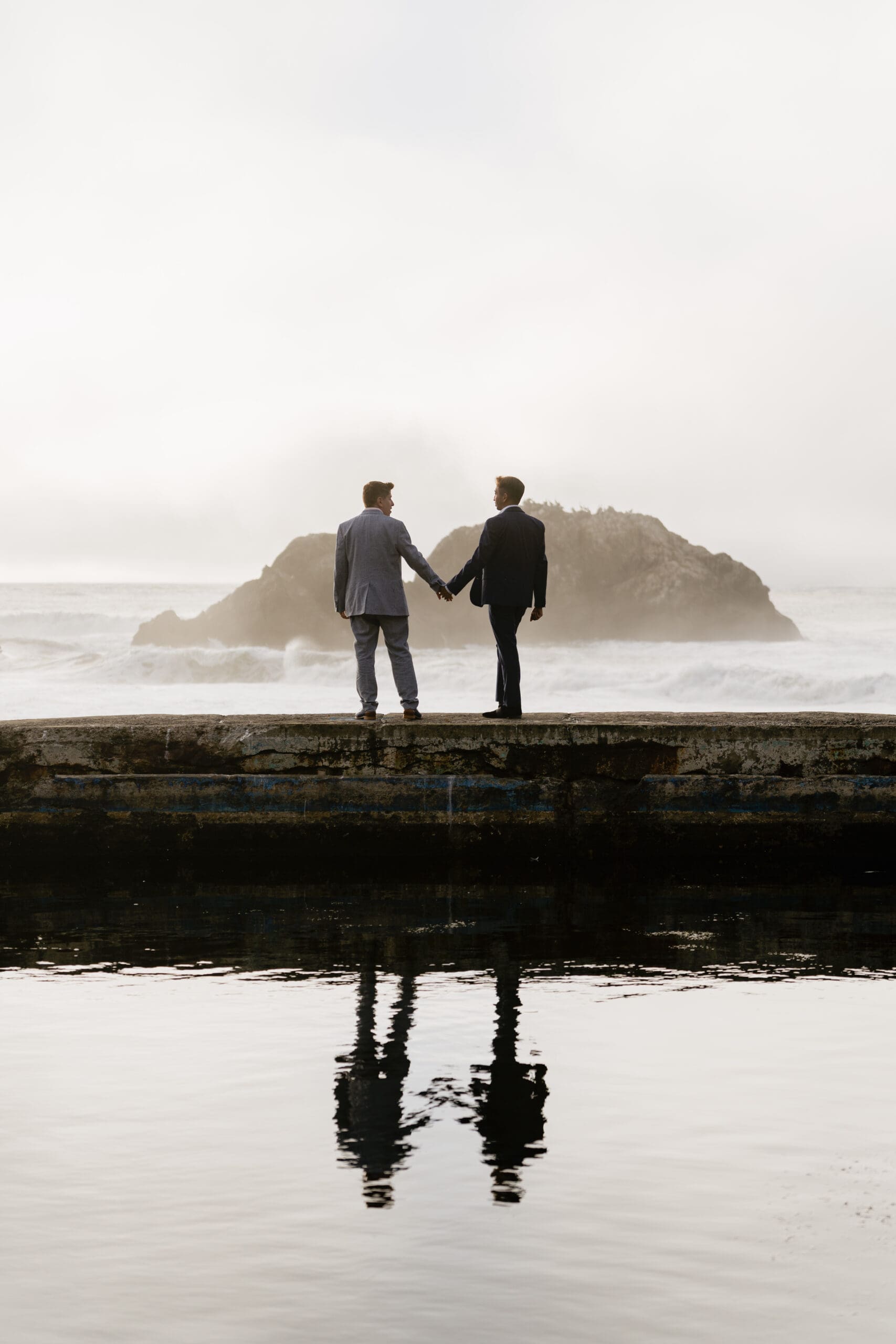Engaged couple during sunset at Sutro Baths in San Francisco, with waves in the background