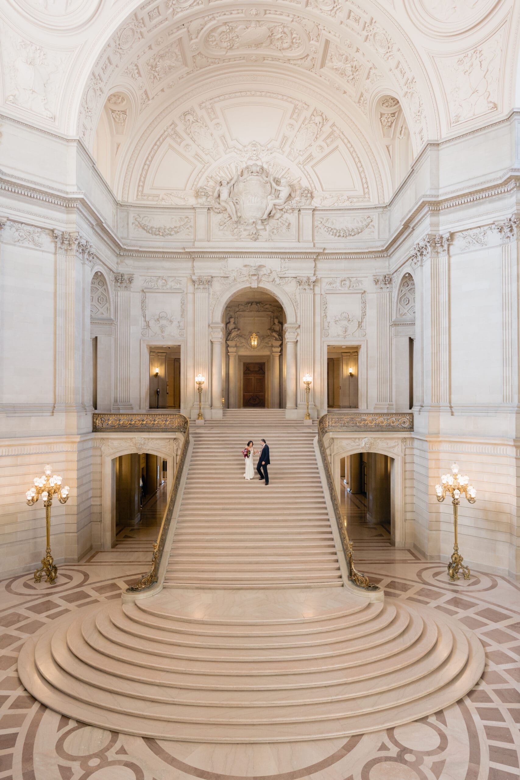 Newlyweds standing at the base of the Grand Staircase at San Francisco City Hall.