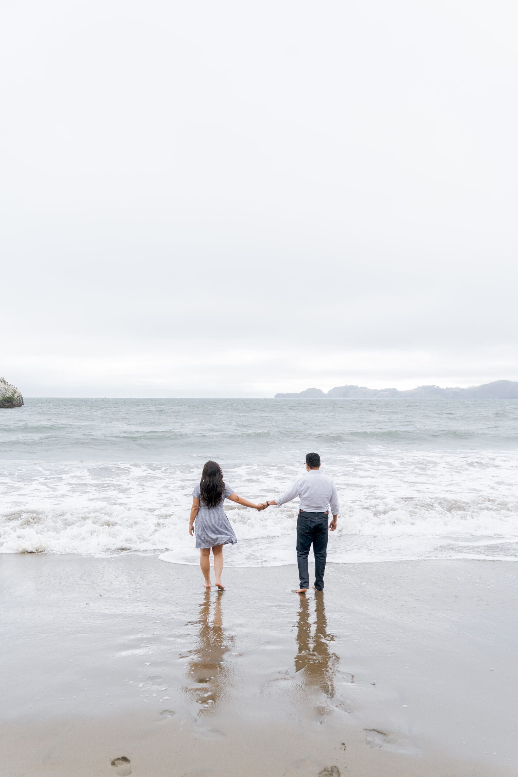 Barefoot couple at the water at Marshall's Beach in SF