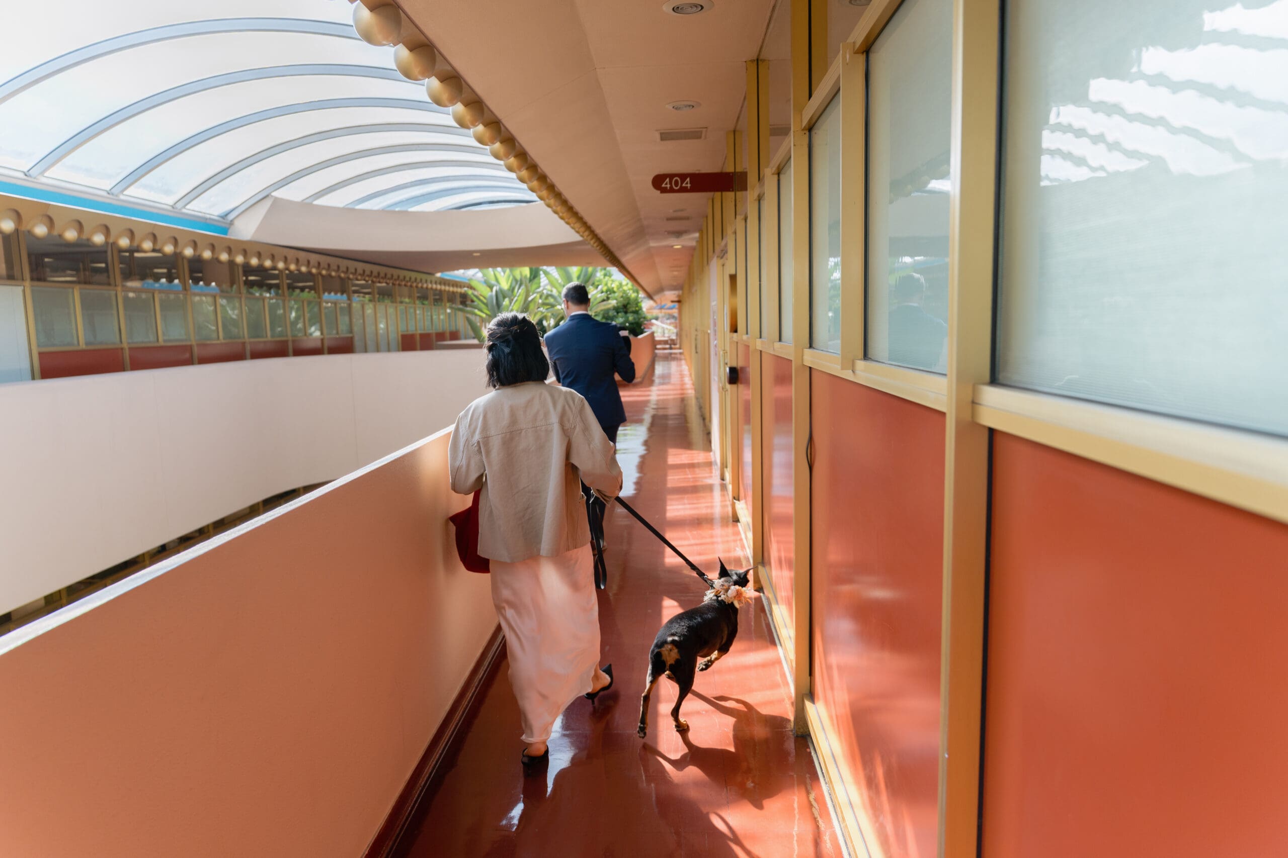 Bride and groom holding hands in a sunlit Frank Lloyd Wright corridor.