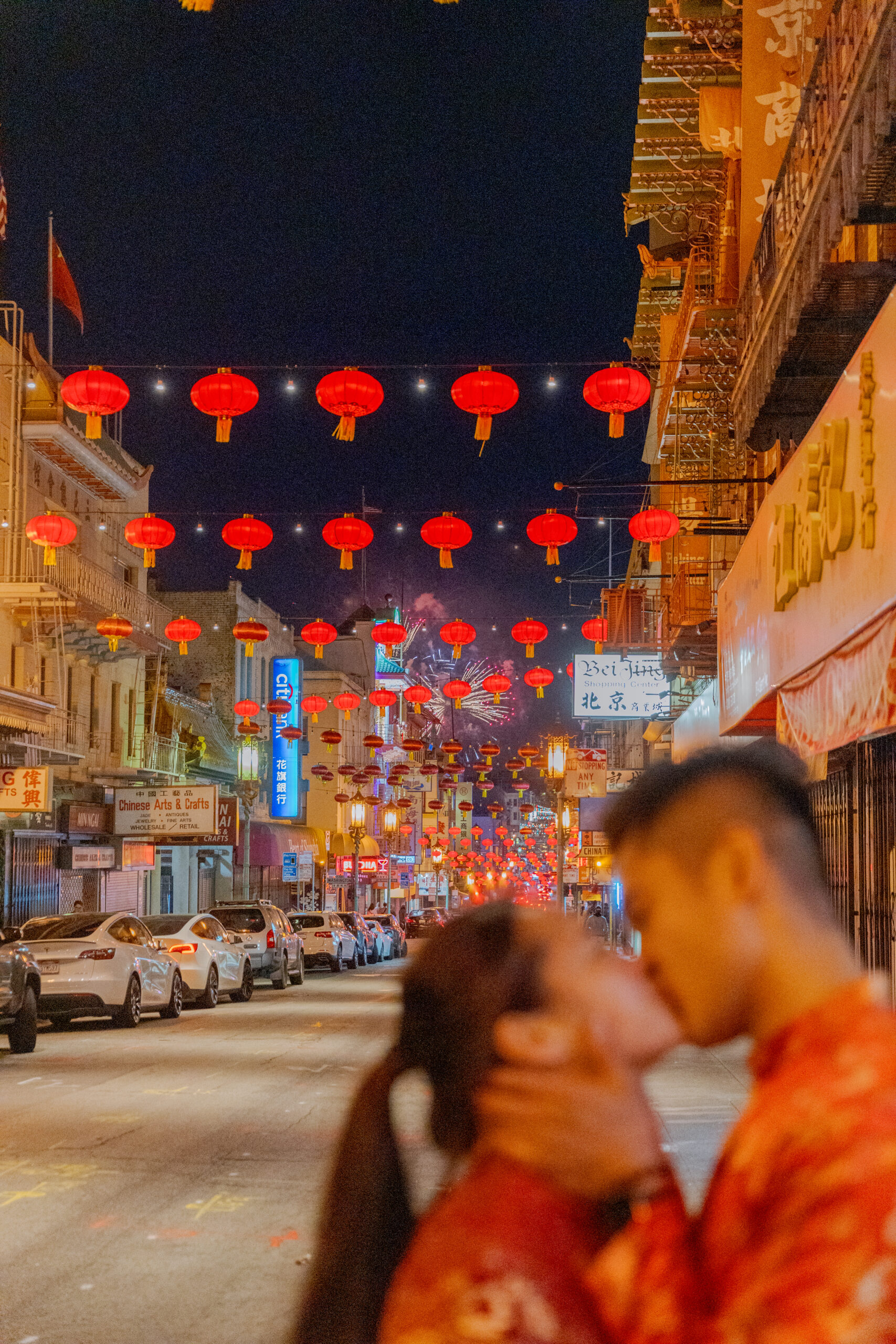 Fireworks in the background while a couple kisses during their engagement photoshoot