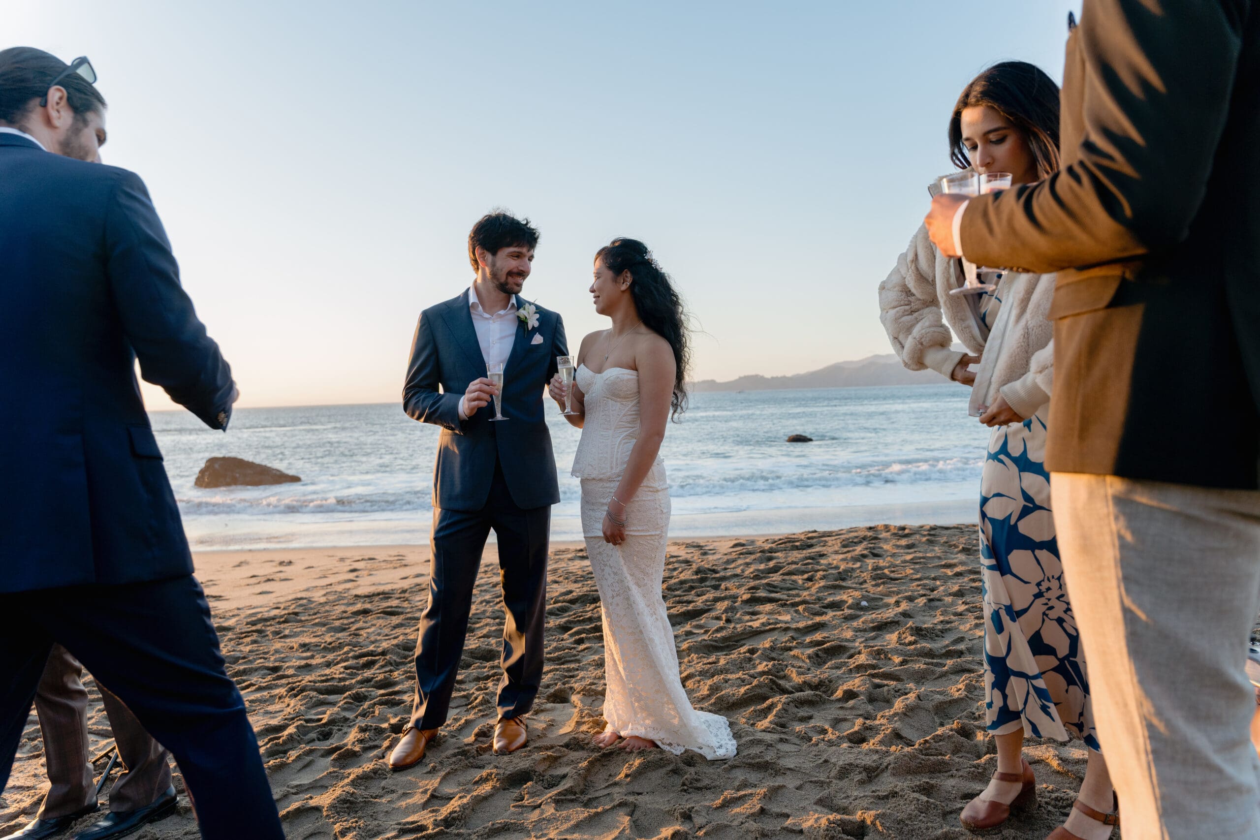 Newlyweds have a celebratory toast on Marshall's Beach in San Francisco after their elopement