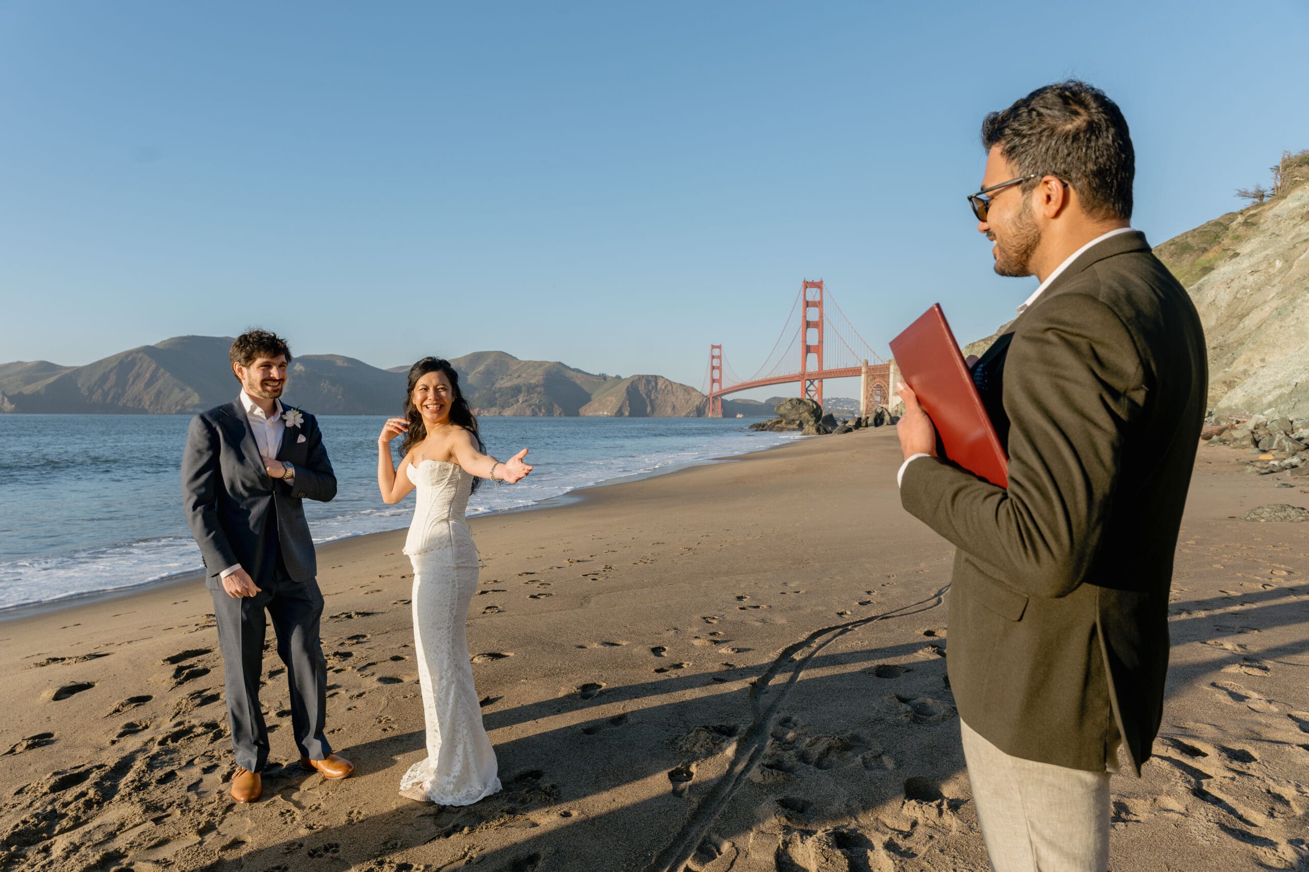 Intimate wedding ceremony at Marshall's Beach with an officiant and the Golden Gate Bridge as the backdrop.