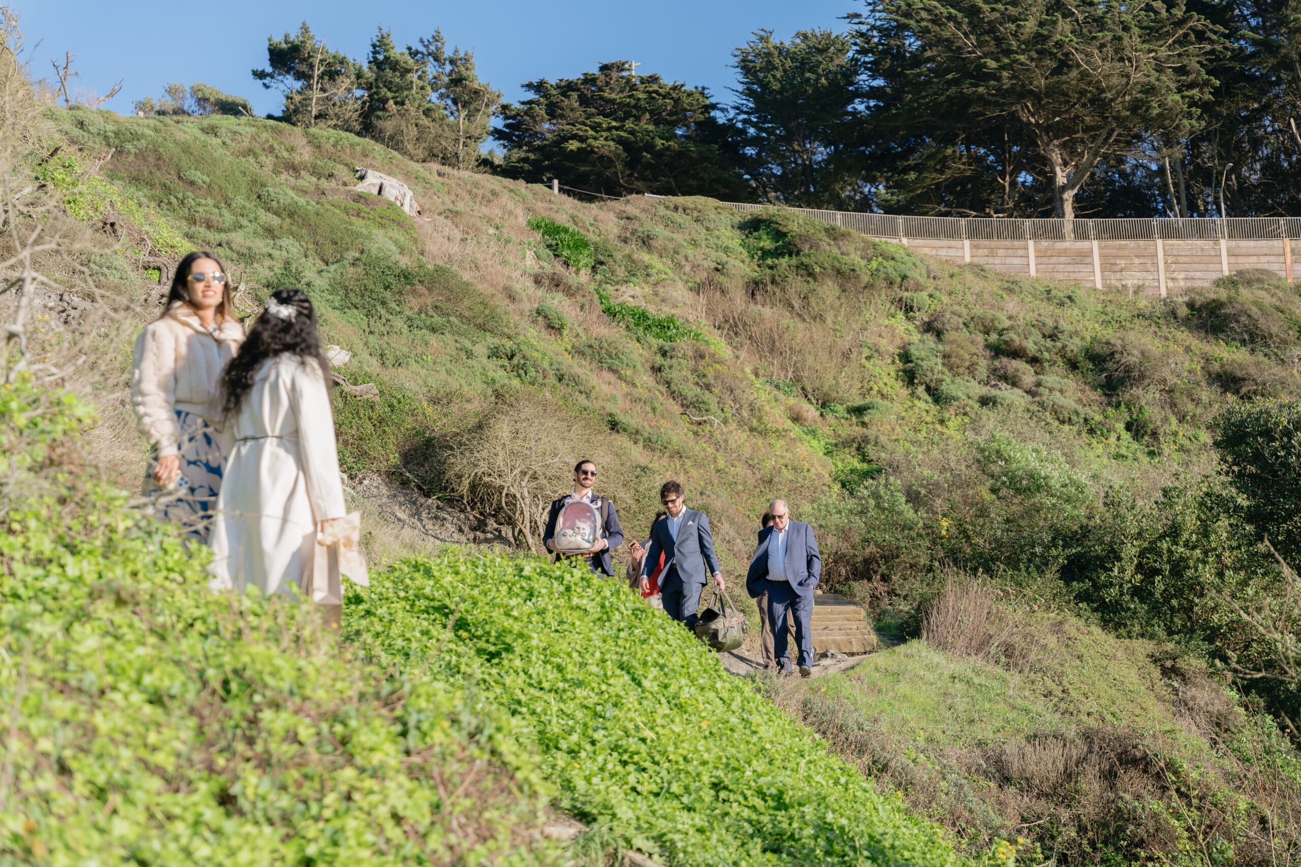 Wedding party hiking batteries to bluffs to get to the elopement spot on Marshall's Beach