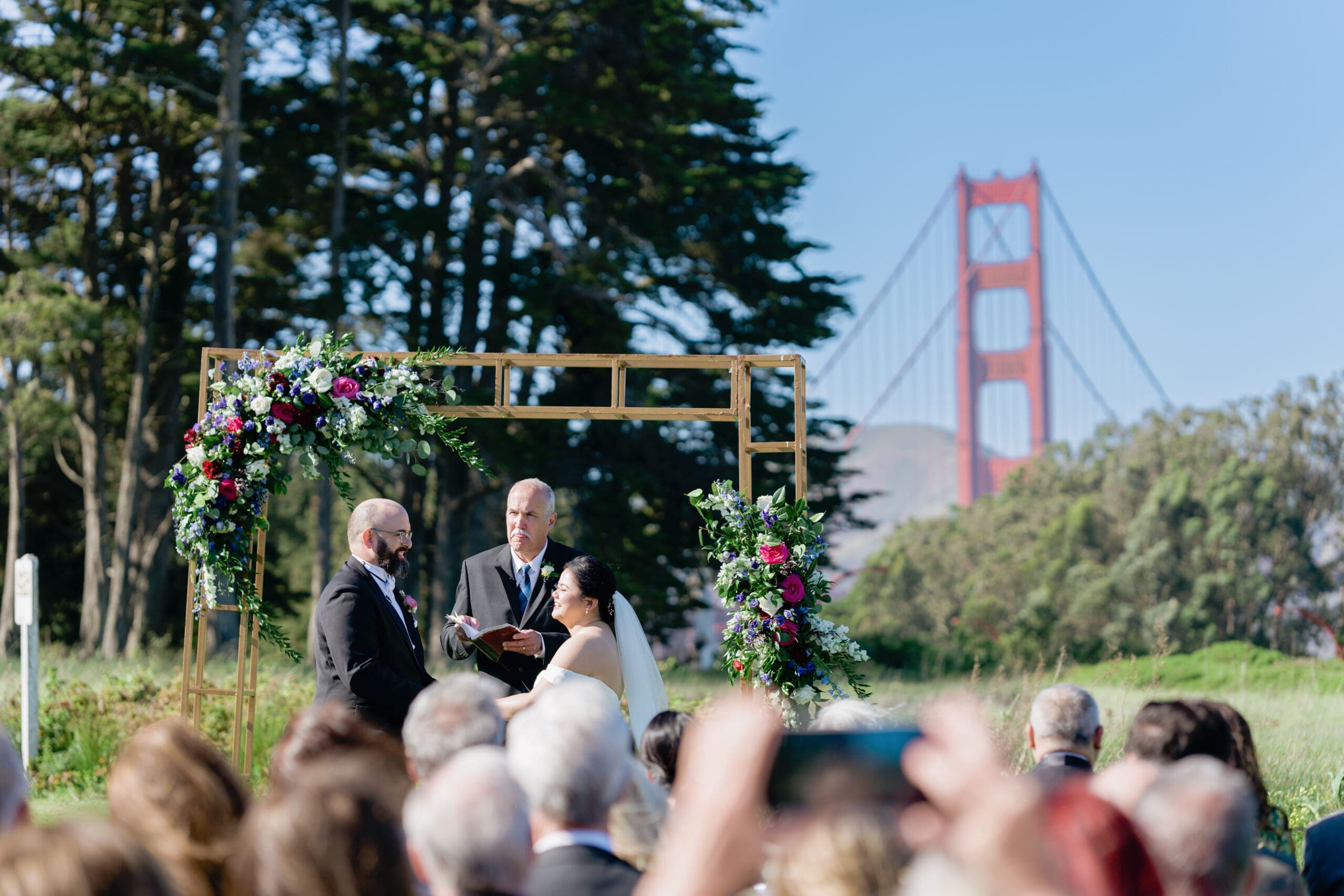 Bride and Groom at the alter with the Golden Gate Bridge in the background at the Log Cabin