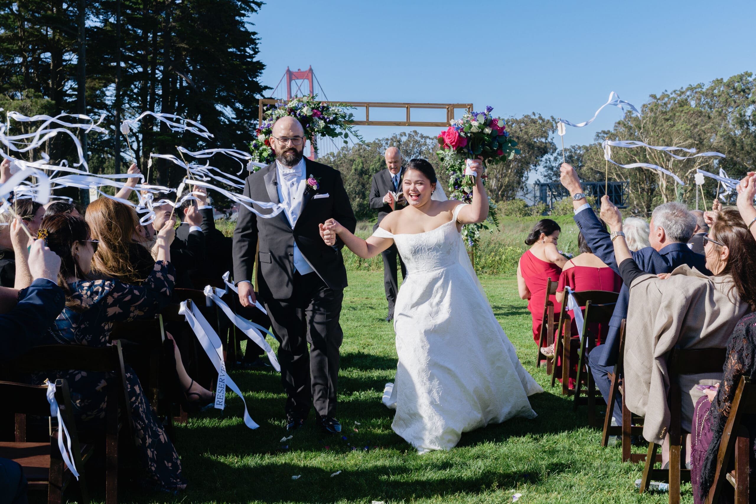 Newlyweds walking back up the aisle after saying I do with cheering crowd