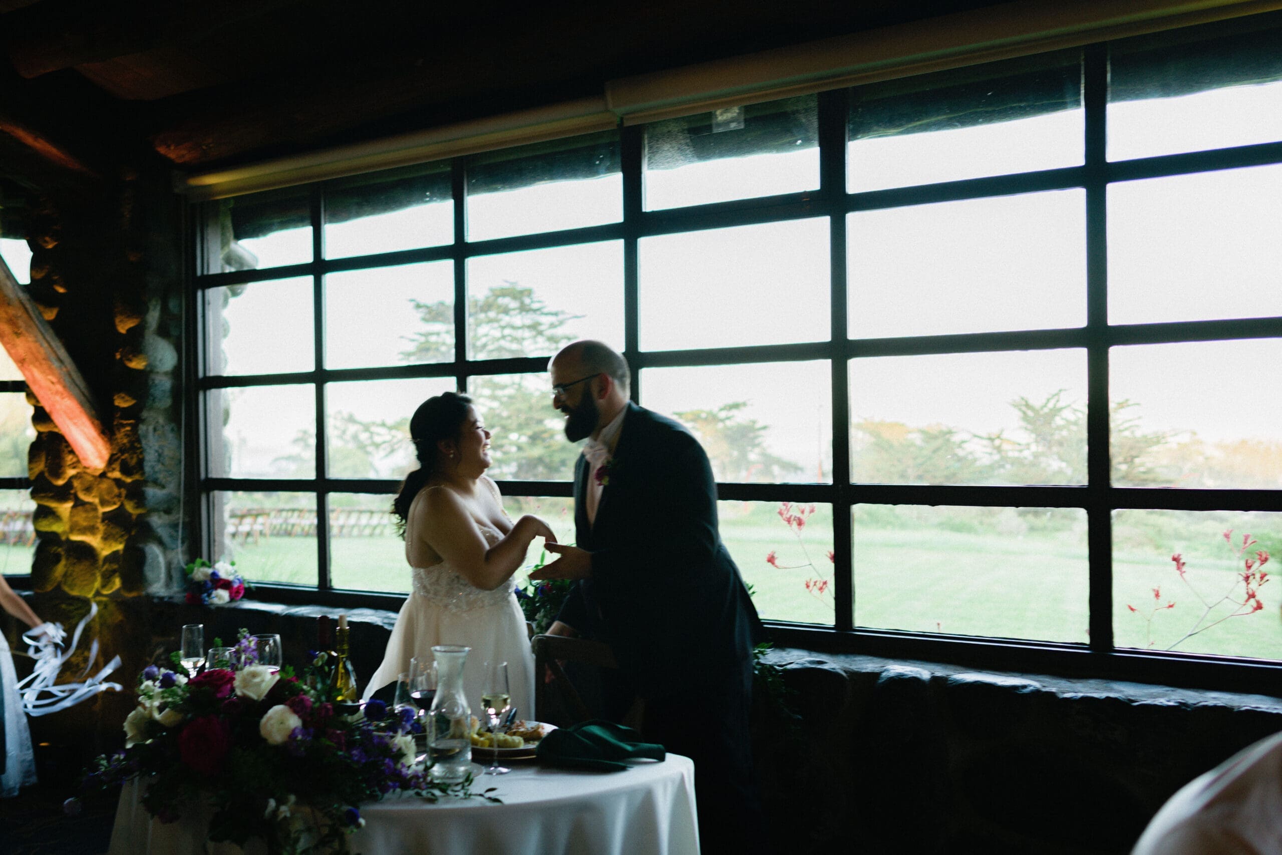 Bride and groom share a candid moment at their sweetheart table during their Log Cabin reception