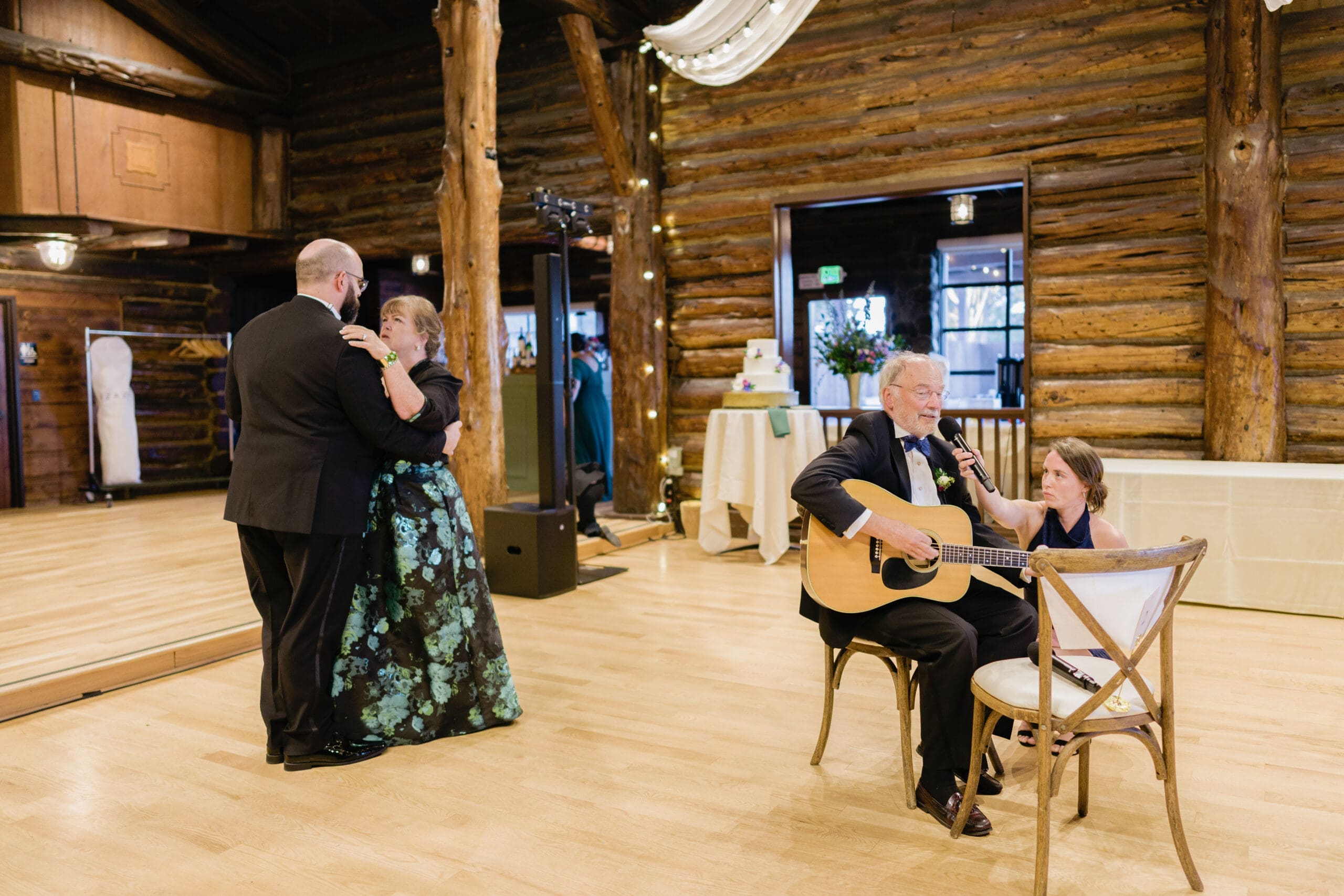 Mother and son dance at the Log Cabin, while father of the groom plays the guitar