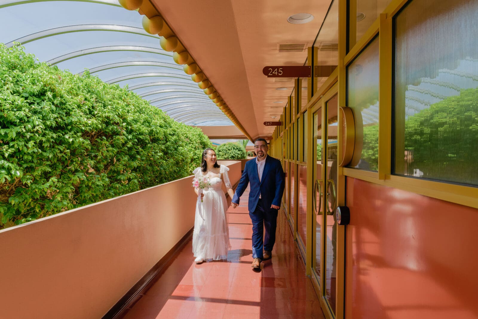 Bride and groom walking down the dramatic colorful sunlit Marin City Hall